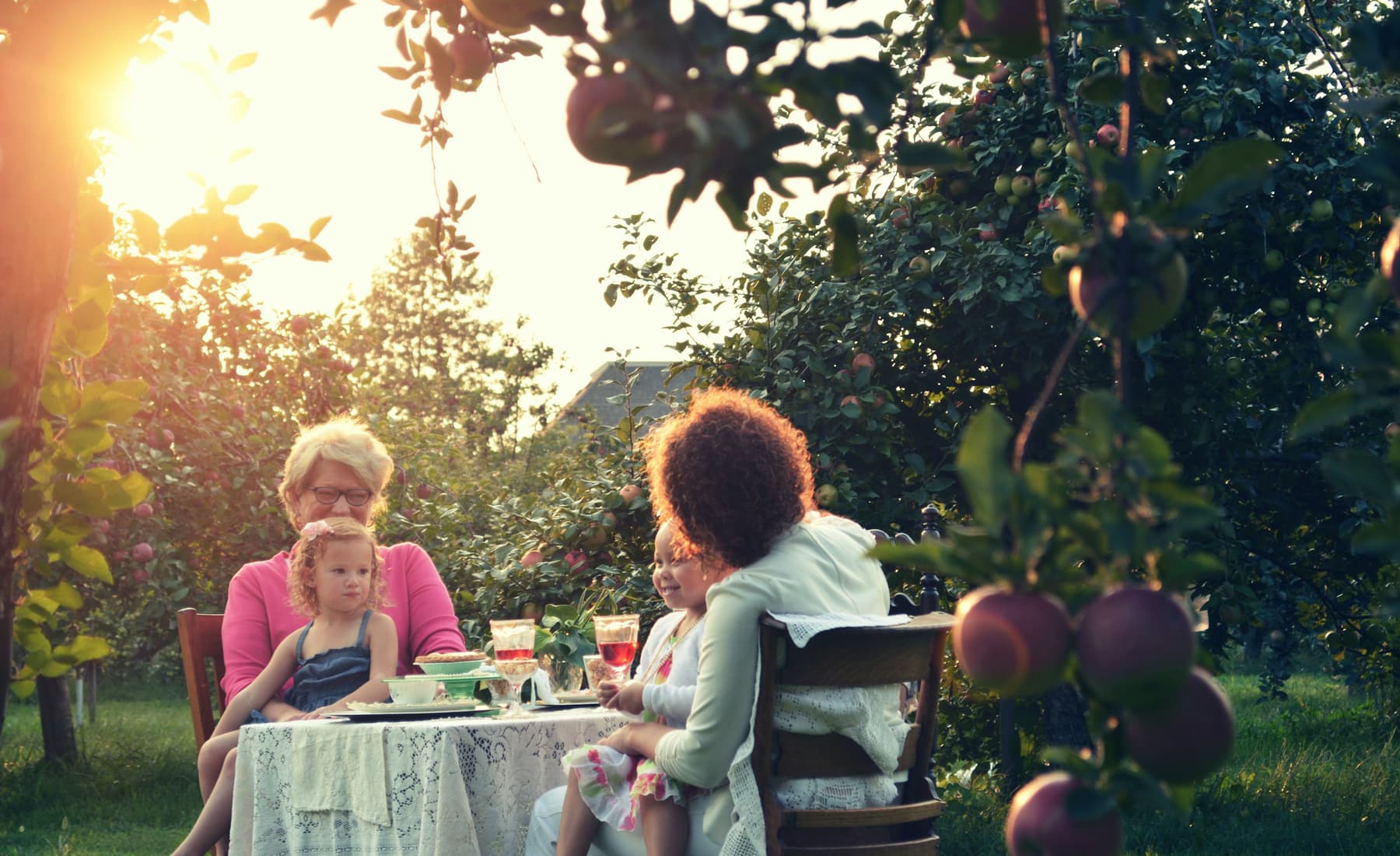 Two women sharing a table in a garden at golden hour