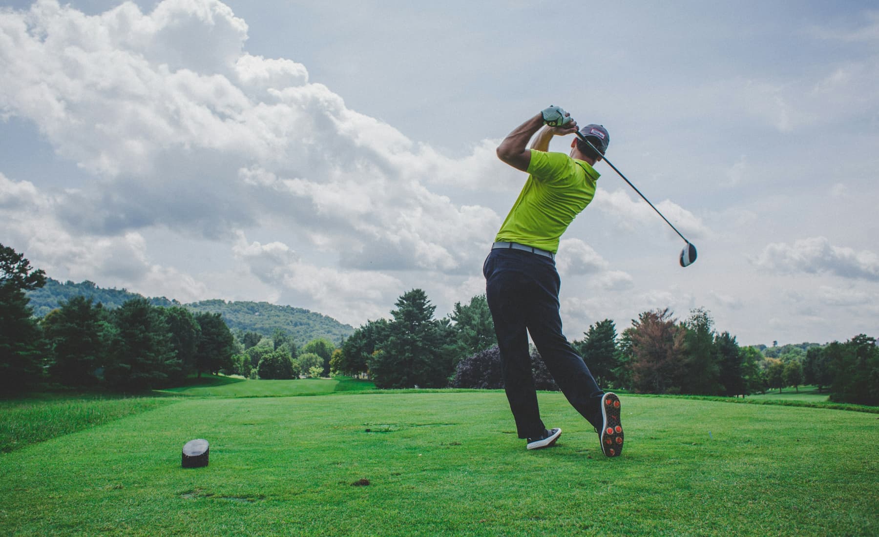 A golfer at the top of a swing on an open green course