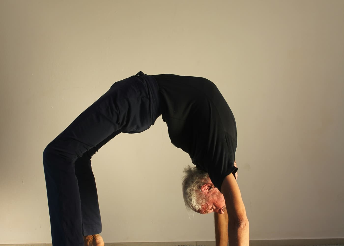 A person with grey hair holding a bridge pose